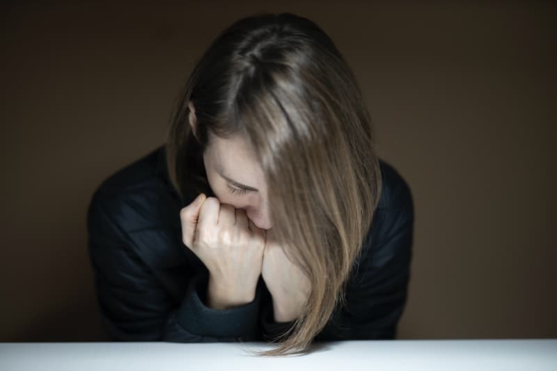 mulher encostada à mesa com as mãos no queixo