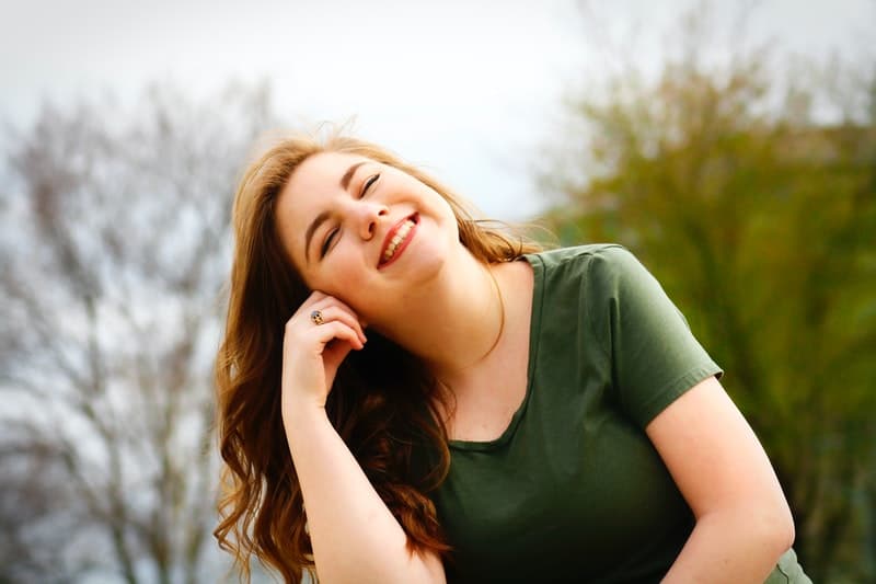 woman leaning head smiling wearing green shirt