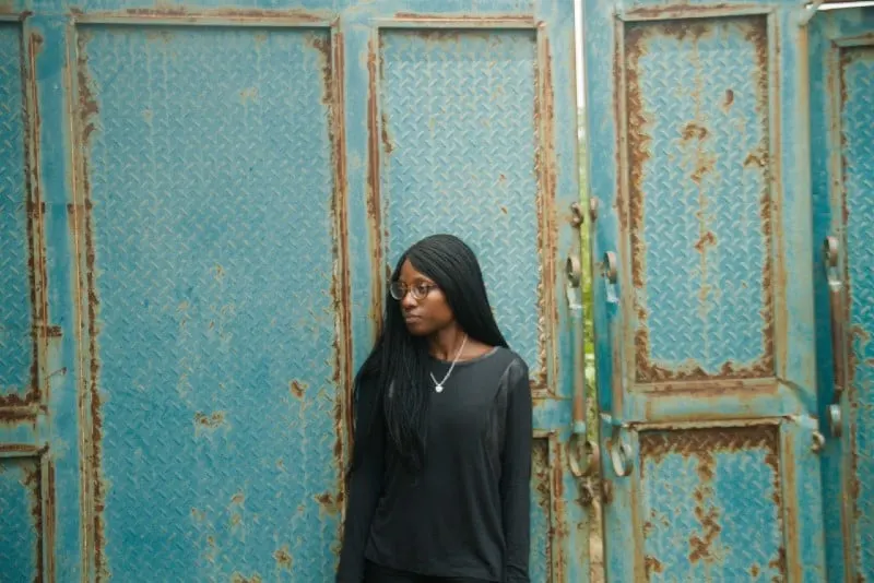woman leaning on blue door at daytime