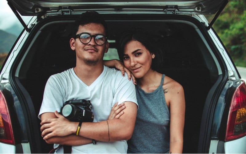 Woman leaning on man's shoulder beside car during daytime