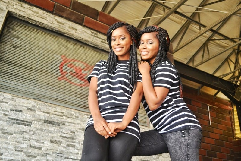 two female twins wearing striped shirts and standing outdoor