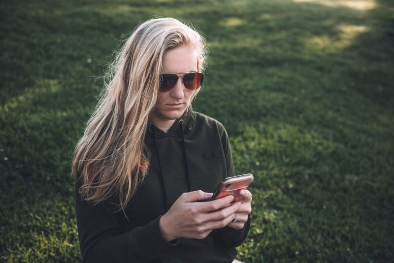 blonde woman with sunglasses looking at phone