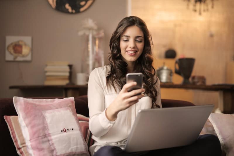 mujer sentada en el sofá y mirando el teléfono