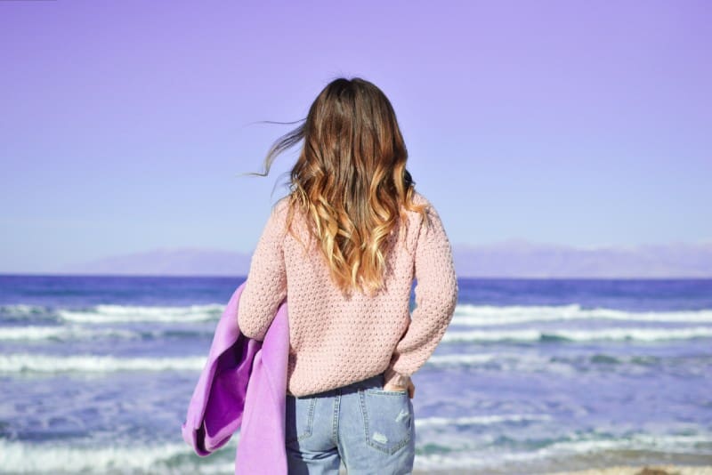 woman in sweater with hand in pocket standing at beach