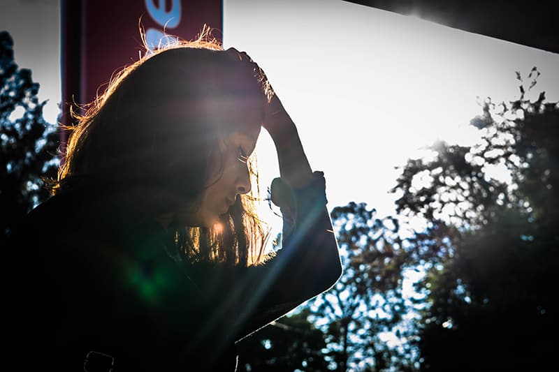 woman looking down while holding head with her hand