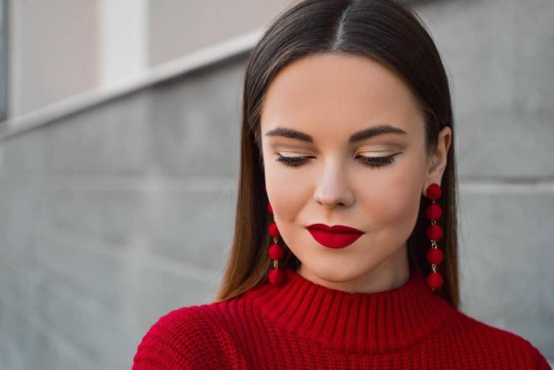 mujer mirando hacia abajo con top rojo y labios rojos