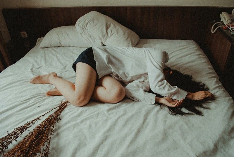 donna sdraiata sul letto con lenzuola bianche