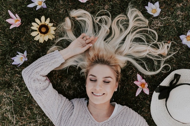 blonde woman in sweater lying on grass