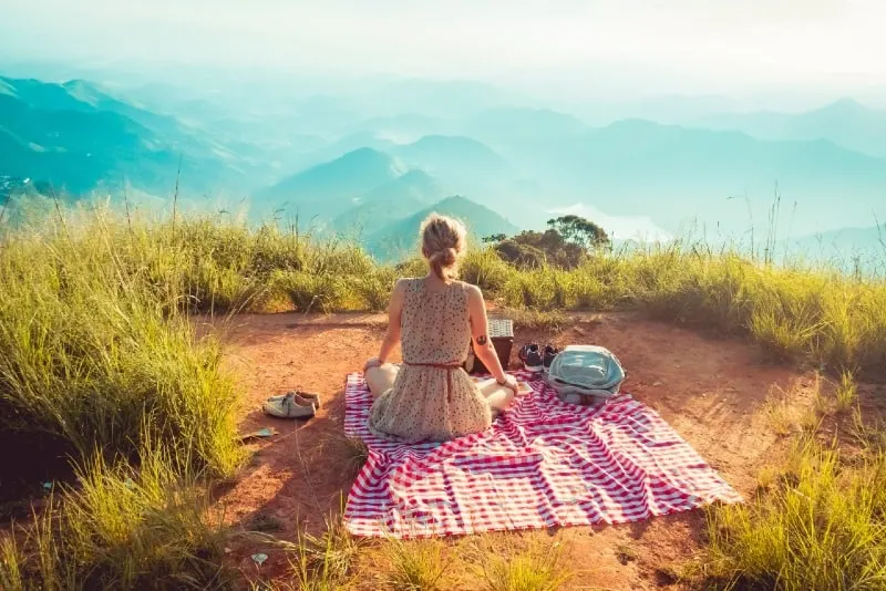 woman in sleeveless dress sitting on picnic mat