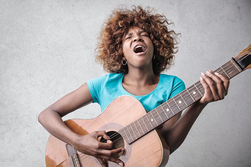 mujer tocando la guitarra acústica mientras canta