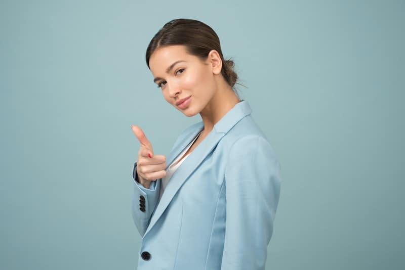 woman pointing her finger wearing blue shawl lapel suit jacket