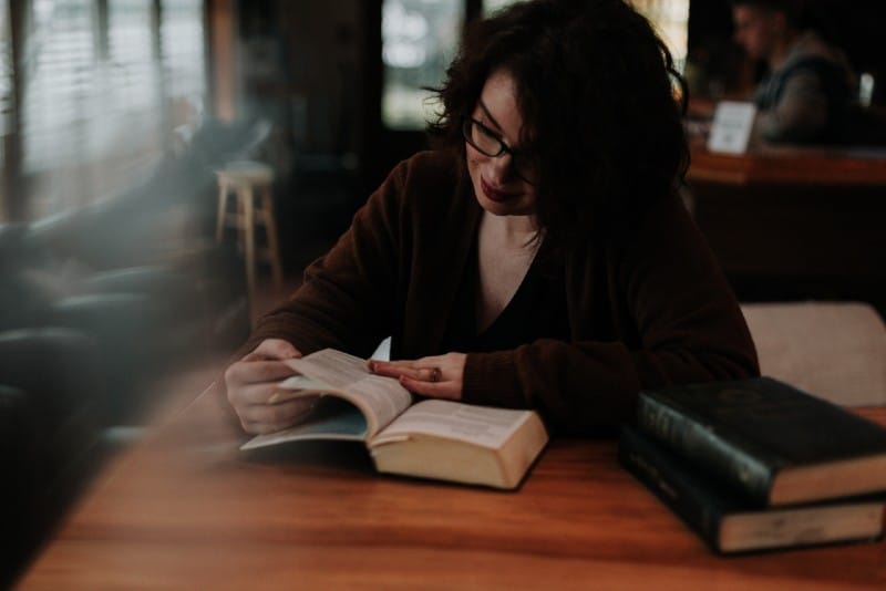 donna con camicia marrone a maniche lunghe che legge un libro