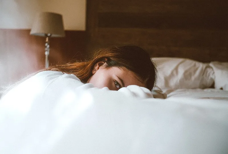 woman resting her head on bed during daytime