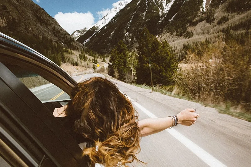 woman riding on vehicle putting her head and right arm outside 