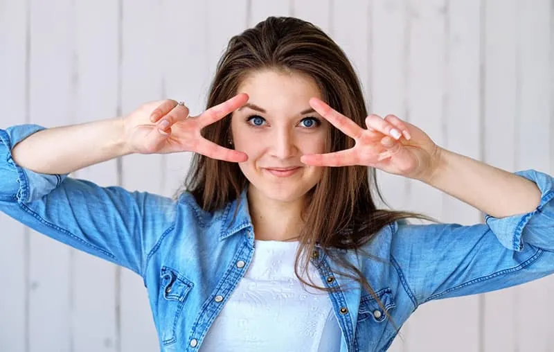 woman showing hand sign of two peace sign near her eyes