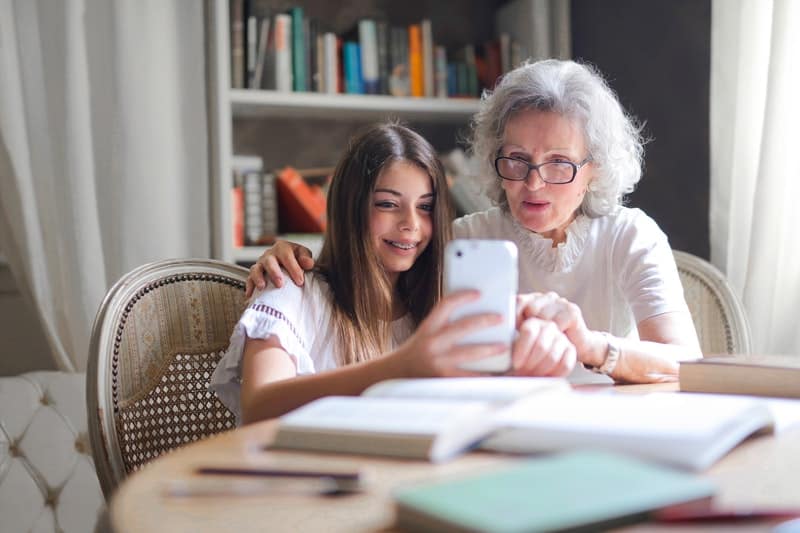 woman showing her cellphone to an old woman while on the table