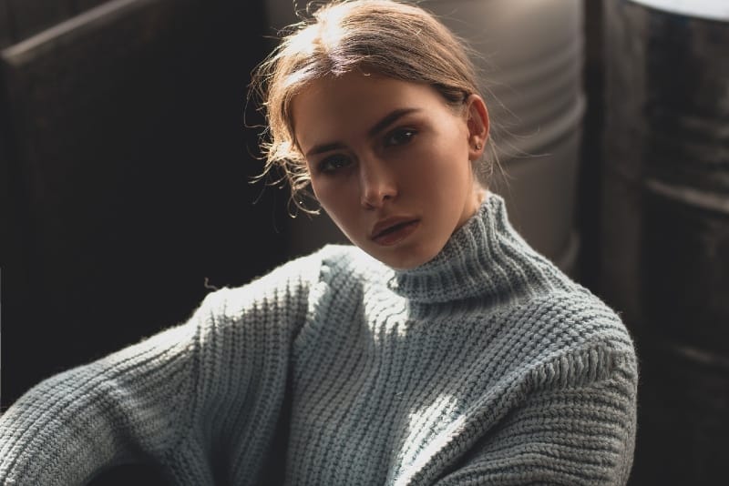 woman in gray turtleneck sweater sitting indoor