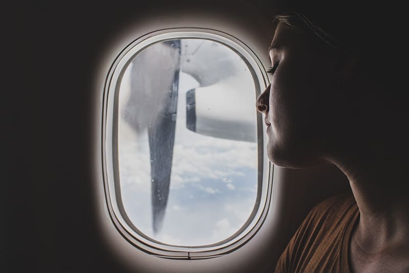 woman sitting near airplane window while sleeping