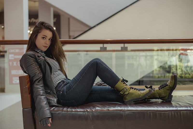 woman sitting on a leather padded sofa in green boots