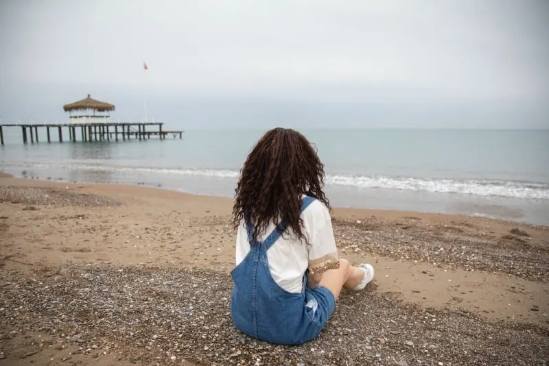 woman sitting on beach looking at sea