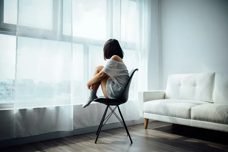 woman sitting on black chair in front of glass-panel window 