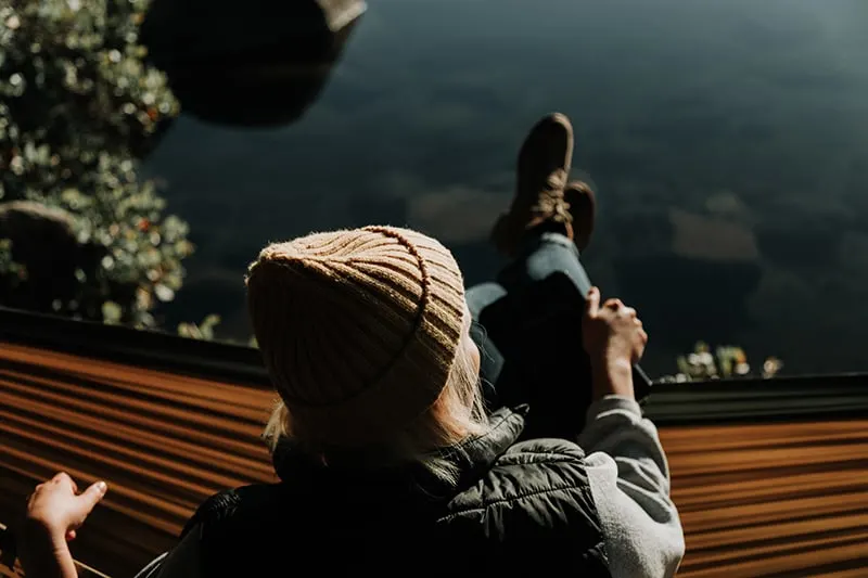 woman sitting on brown hammock while looking far away