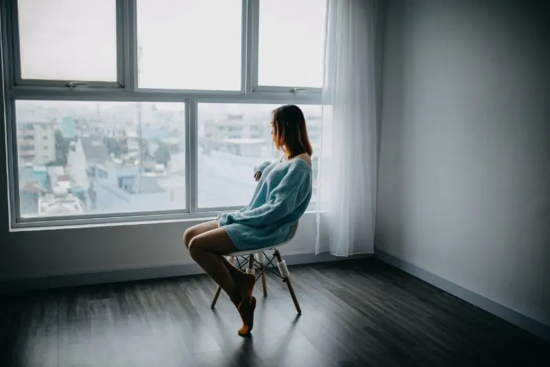woman sitting on brown chair beside glass window
