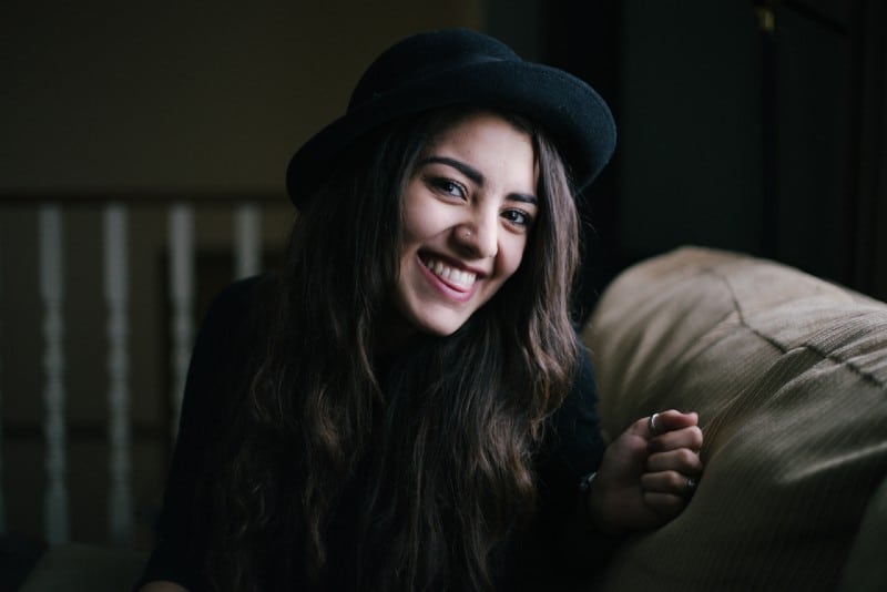 woman with black hat sitting on couch and smiling