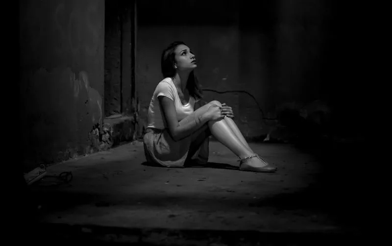 black and white photo of sad woman sitting on floor