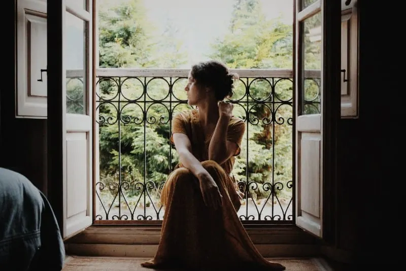 woman in maxi dress sitting on floor near window