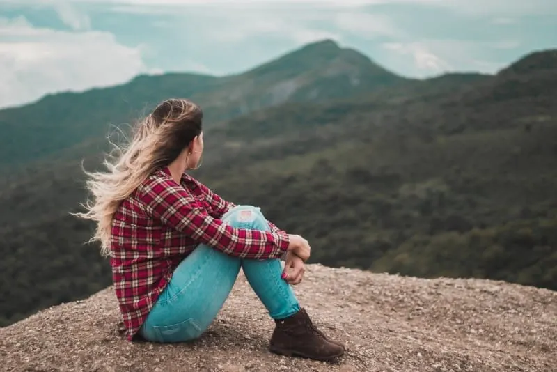 woman sitting on ground looking at mountain