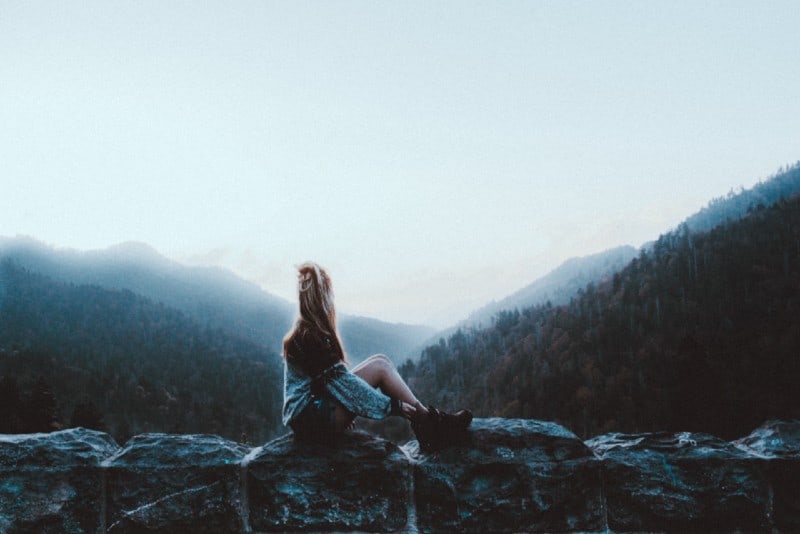 donna seduta su roccia grigia di fronte a montagne verdi
