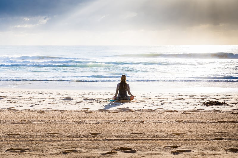 woman sitting on seashore during daytime