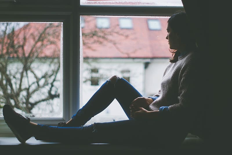 mujer sentada en la ventana mirando la calle