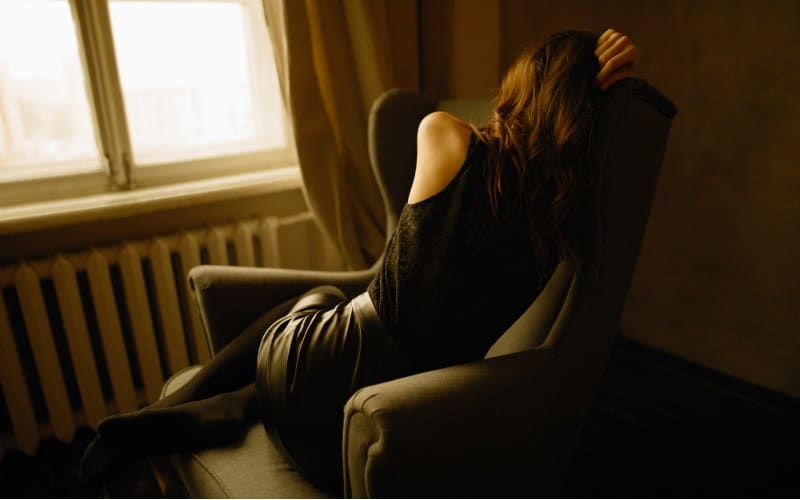 mujer sentada en un sillón junto a la ventana