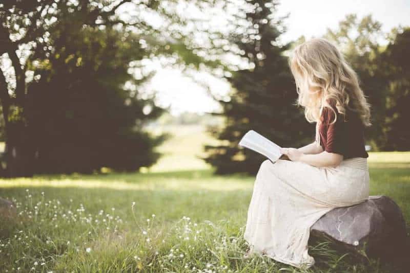 woman sitting while reading a book