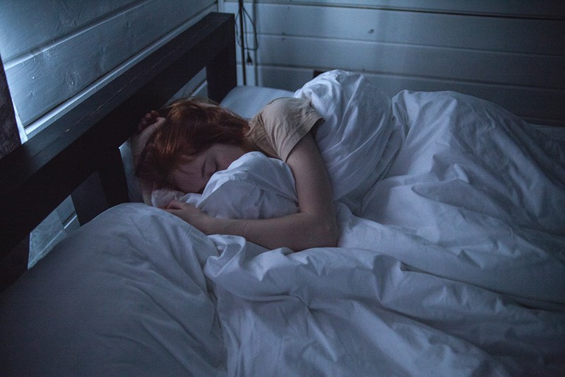 donna che dorme nel letto coperto da una coperta bianca