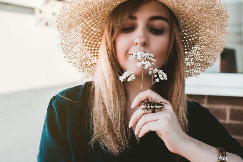 woman smelling white flowers