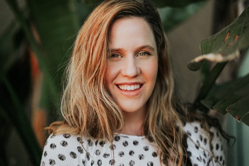 smiling woman standing near plant