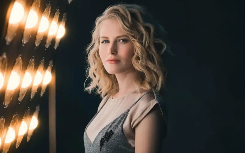 Young blonde woman standing beside lights