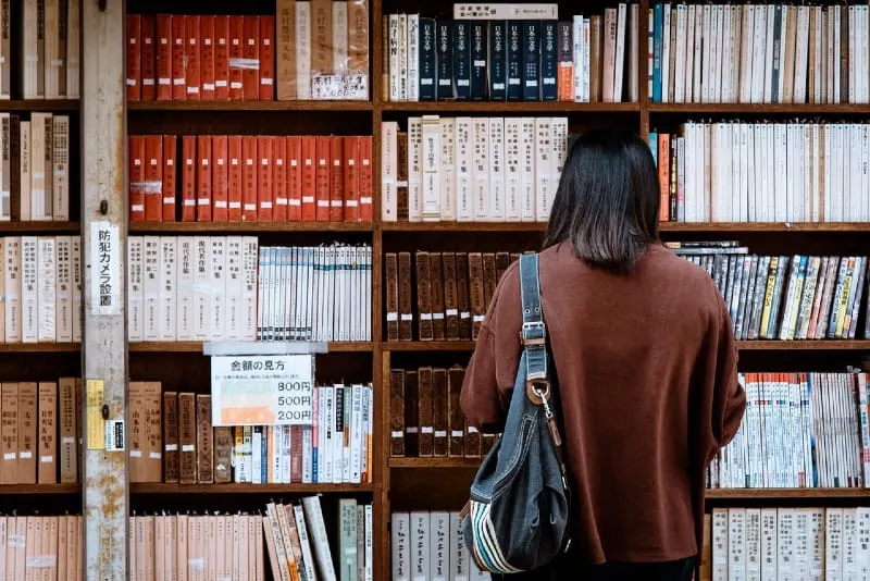 woman in brown shirt standing in front of library books