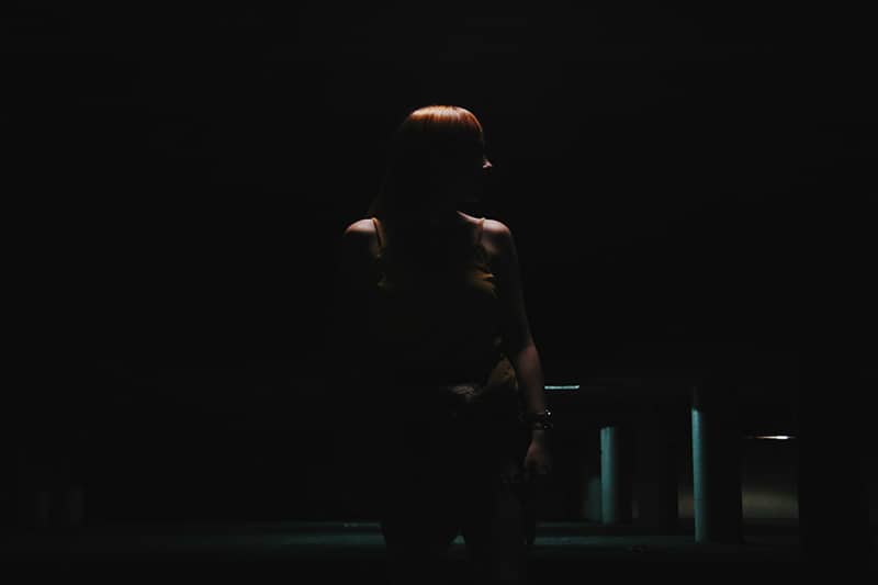 donna che carteggia al buio vicino a un parcheggio vuoto