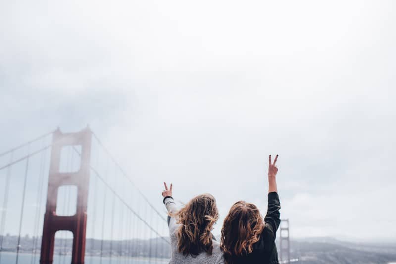 dos mujeres haciendo el signo de la paz cerca del puente Golden Gate