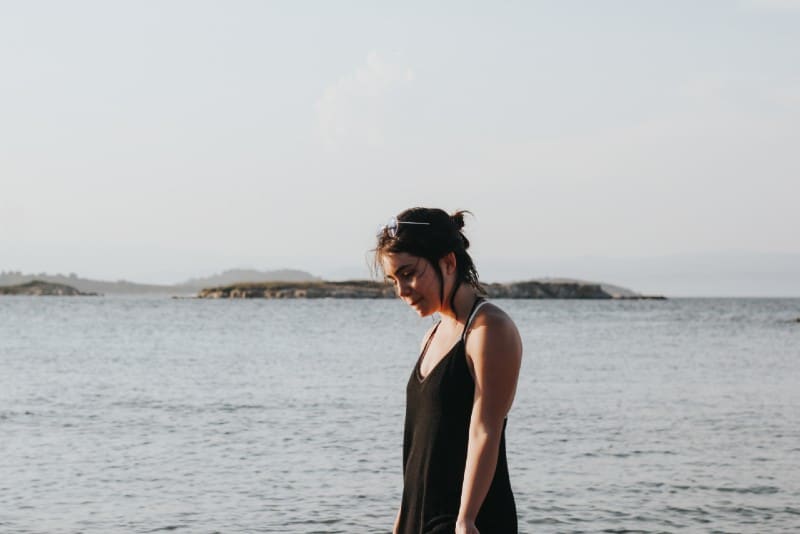 donna in abito nero in piedi vicino al mare durante il giorno
