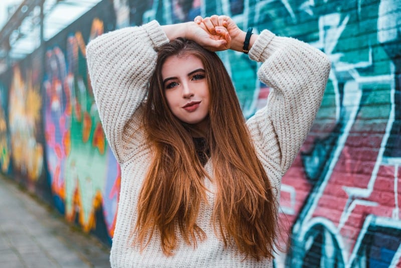 woman in sweater standing near graffiti wall