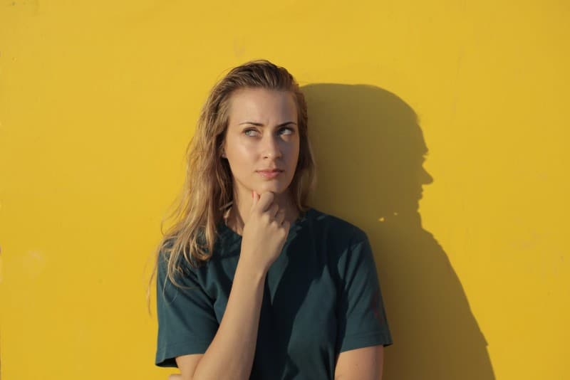 woman standing near yellow wall and thinking
