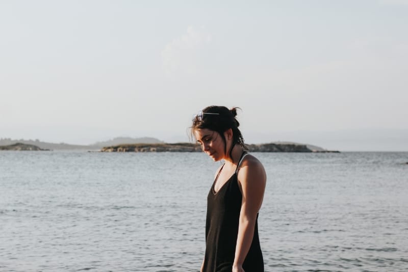 woman in black dress standing near sea