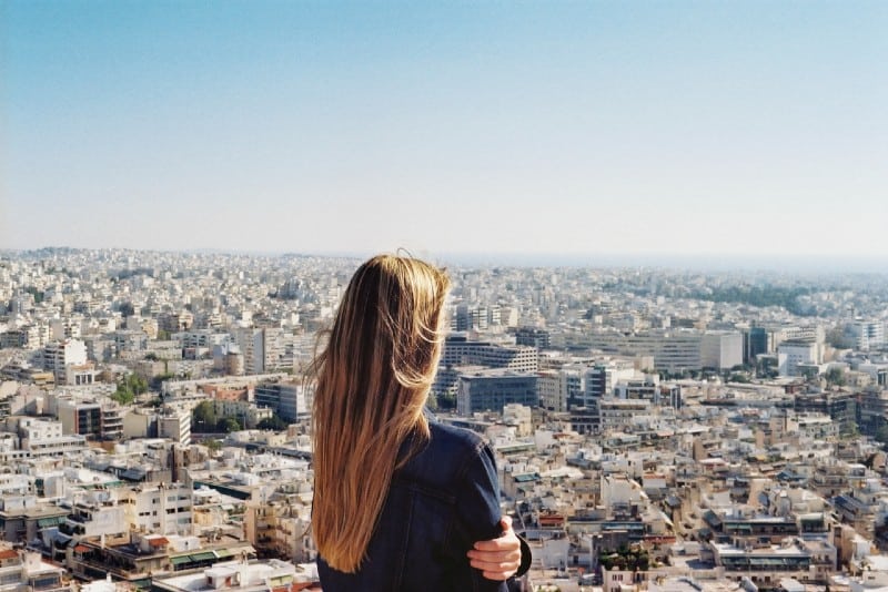 donna in piedi sulla cima di una collina e guardando la città