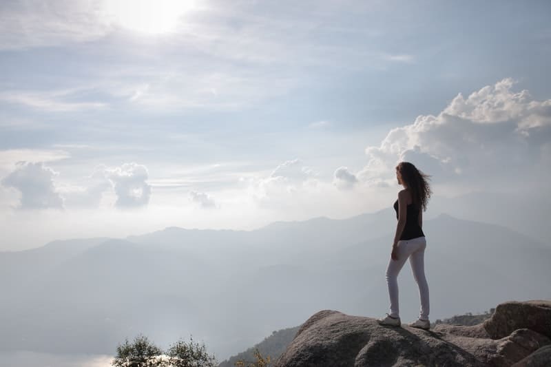 donna in piedi su una roccia che guarda il panorama della natura