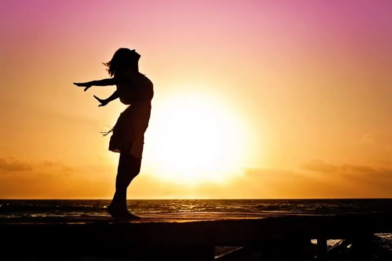 silhouette of woman standing on beach during sunrise